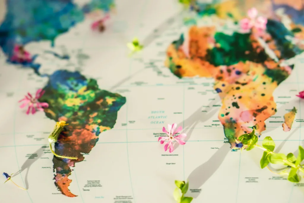 Colorful world map adorned with flowers and green leaves symbolizing global peace and nature.