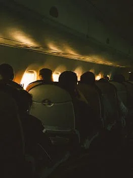 Passengers seated inside a dimly lit airplane cabin during flight. Captures the mood of in-flight travel.