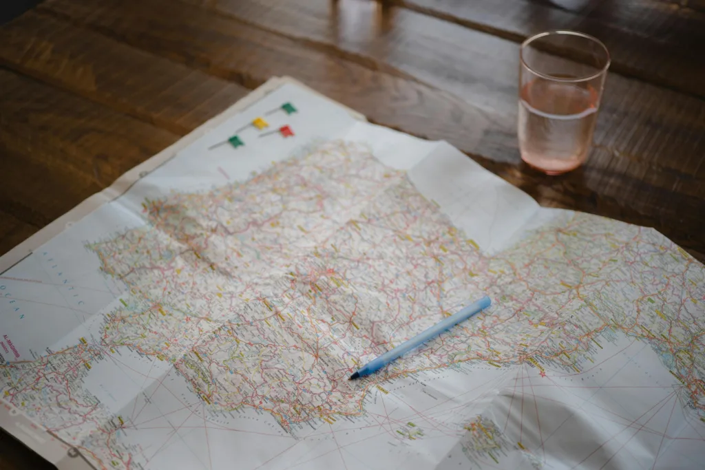 Map highlighting Spain and Portugal with a pen and glass on a wooden table.