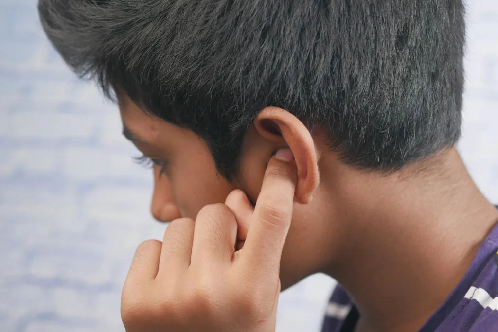 Close-up of a teenager's profile with hand covering ear, reflecting introspection or concentration.