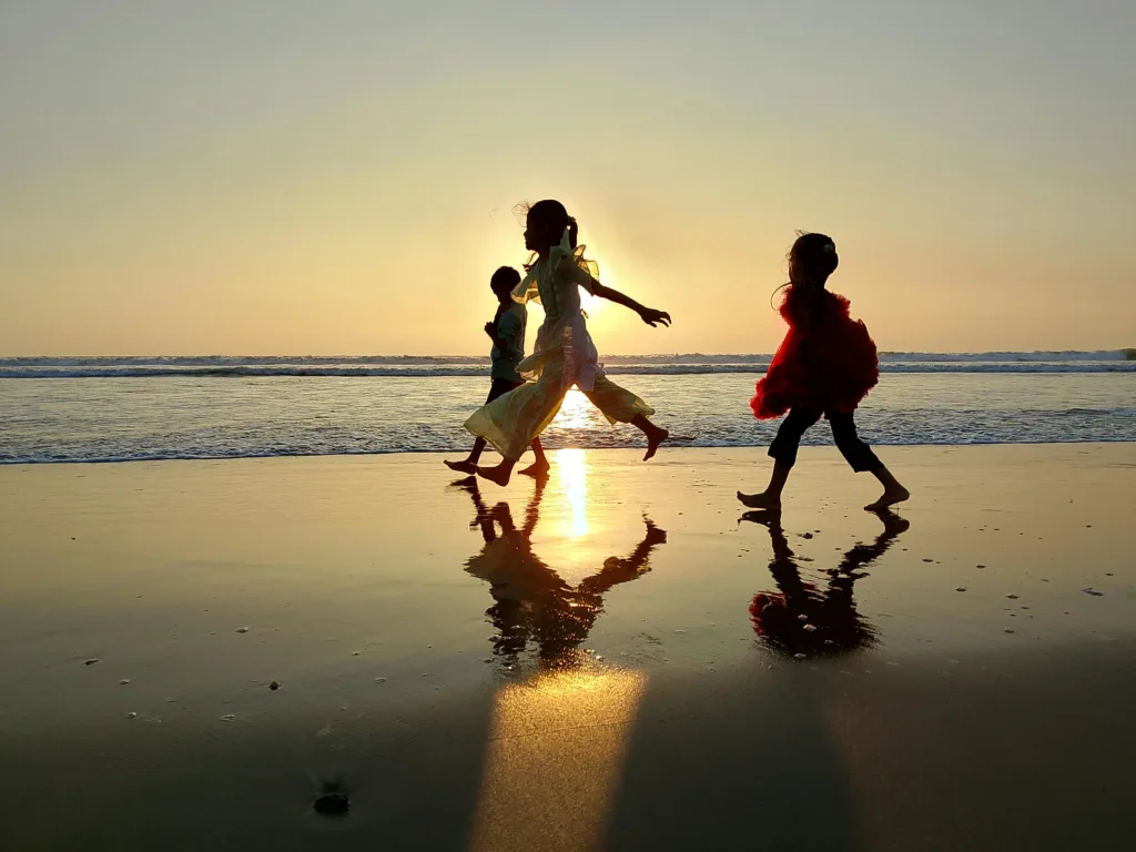 Silhouettes of children running along the beach at sunset in Teknaf, Bangladesh.